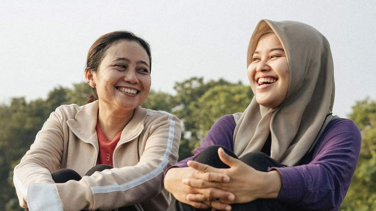 Two women sit outdoors and laugh together